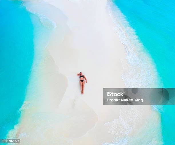 Beautiful Woman Tans On Sandbank Surrounded By Turquoise Ocean From Above Stock Photo - Download Image Now