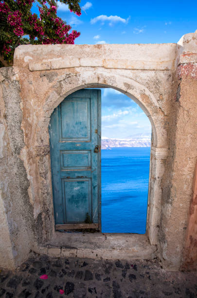 an old door in santorini with a beautiful view behind - greece blue house wall imagens e fotografias de stock