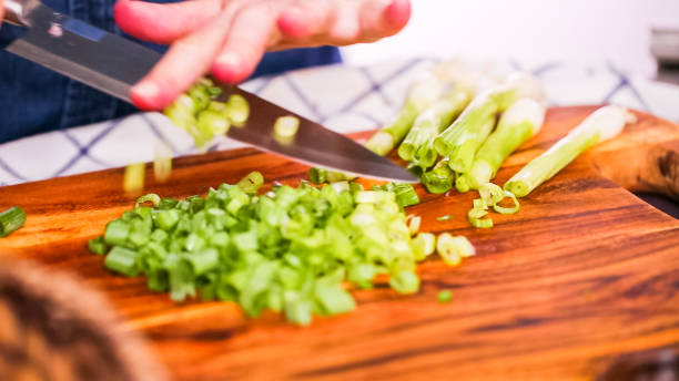 istock Slicing green onions on a wood cutting board. 1021706718