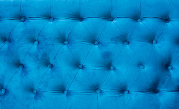 istock Velour surface of sofa close-up. Coach-type velours screed tightened with buttons. Blue chesterfield style quilted upholstery backdrop close up. 1021706912