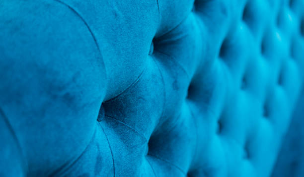 Velour surface of sofa close-up. Coach-type velours screed tightened with buttons. Blue chesterfield style quilted upholstery backdrop close up. stock photo