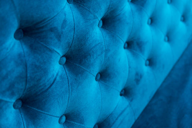 istock Velour surface of sofa close-up. Coach-type velours screed tightened with buttons. Blue chesterfield style quilted upholstery backdrop close up. 1021707072