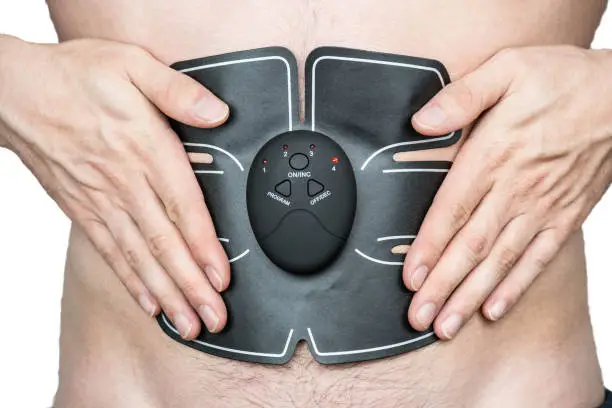 Photo of Male athlete wearing a electric ab muscle stimulator doing abs exercise