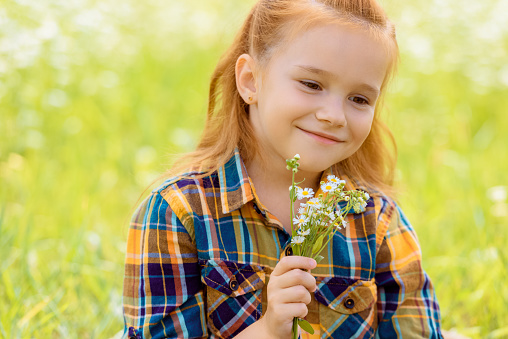 portrait of smiling child with bouquet of wild flowers in hand