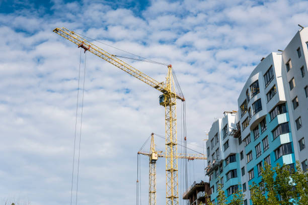 istock Crane and building under construction against blue cloudy sky. 1021725420