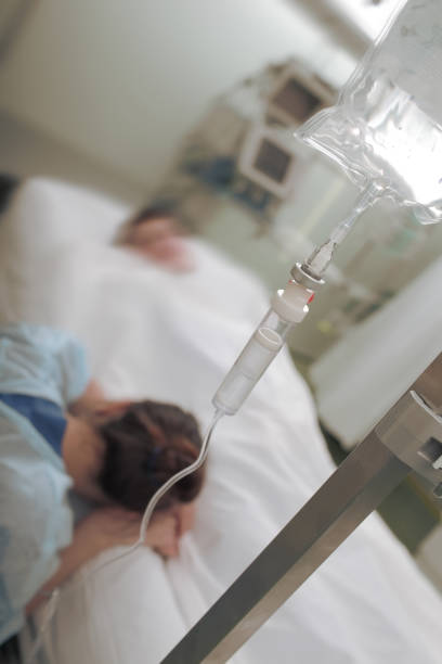 crying woman at the man's bedside in hospital - iv drip chemotherapy drug bag intensive care unit imagens e fotografias de stock