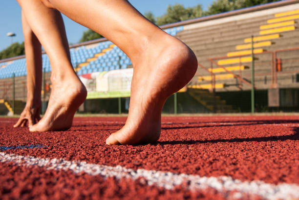 piedi nudi pronti a partire su una corsia rossa dell'anello atletico - depart foto e immagini stock