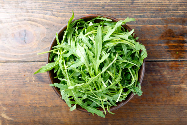 istock fresh arugula on a wooden background top view. 1021734604