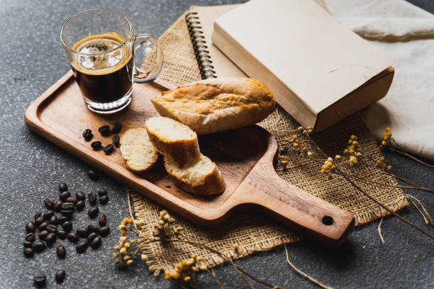 istock A coffee, bread, wood plate and book setting on black background 1021736260