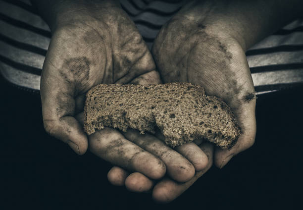 Dirty hands of homeless poor man with piece of bread. The concept of poverty and social inequality. Unemployment and hunger. Consequence of war. The lack of food. Economic crisis. Social inequality. Third world war. Panhandler. Almsman. Shortage of food. money shortage stock pictures, royalty-free photos & images