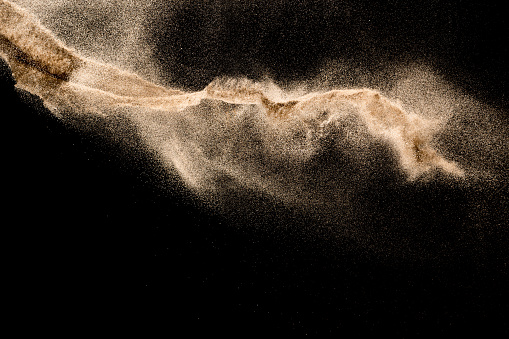 Golden sand explosion isolated on black background. Abstract sand cloud.