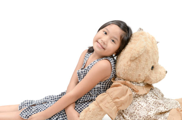 istock Cute girl sitting with big teddy bear isolated 1021750204