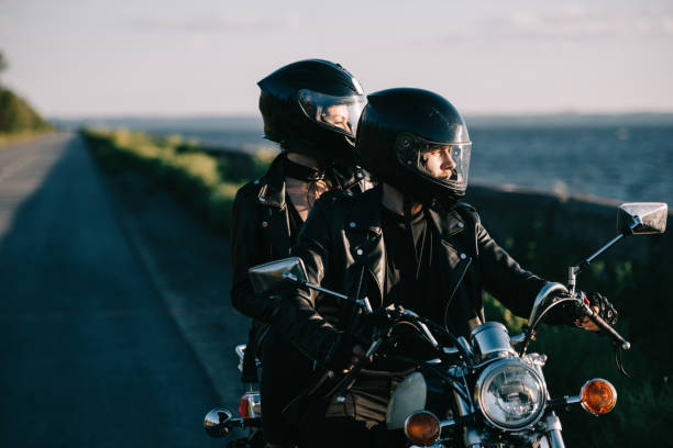 coppia di motociclisti in caschi in sella moto classica su strada di campagna - ridinf foto e immagini stock