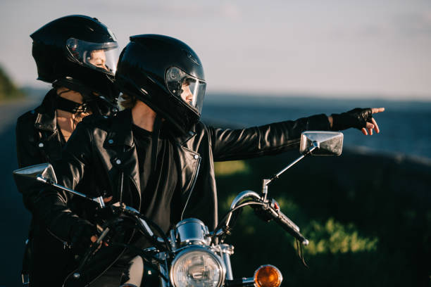 istock bikers in helmets on motorcycle, man showing something to girlfriend 1021758494