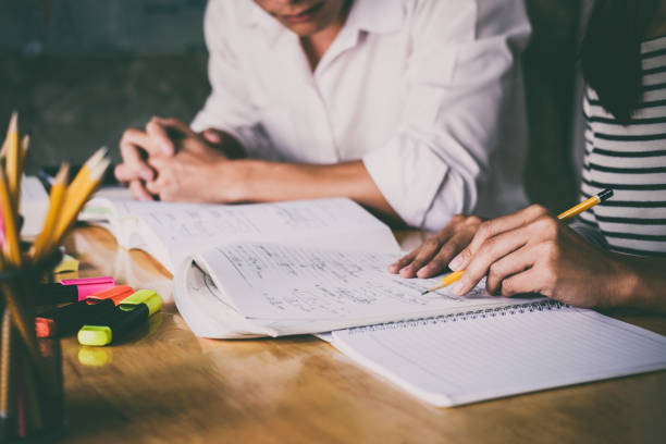 istock High school or college student group catching up workbook and learning tutoring in classroom and reading, doing homework and lesson practice preparing exam 1021759312