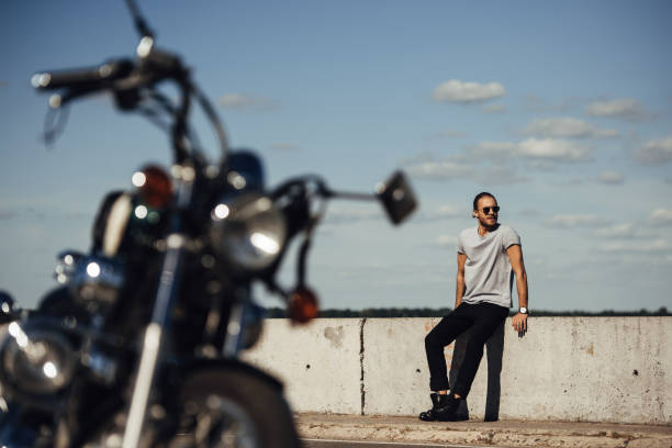 istock selective focus of young biker with classic motorcycle on foreground 1021766138