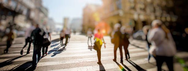 folla di persone che camminano su strade soleggiate - defocused crowd blurred motion business foto e immagini stock