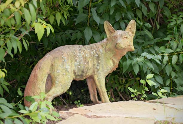 istock Stone sculpture of a fox standing under a bush 1021781986