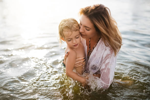istock mother kissing child in river during sunset 1021782650