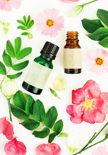 holistic essential oils, green leaves and pink flowers.