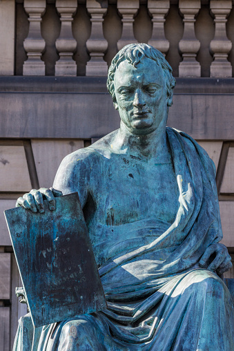 Edinburgh, Scotland, UK - June 13, 2012; Closeup of David Hume green bronze statue outside Court House on Lawnmarket. Beige stone wall as background.