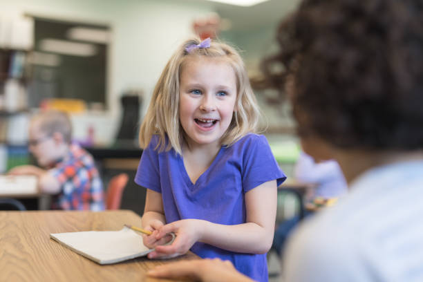 istock First grade girl talking with her teacher in the classroom 1021799520