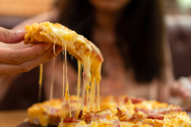 fatia de pizza quente com queijo derretido e fibroso na mão da mulher. - stringy - fotografias e filmes do acervo