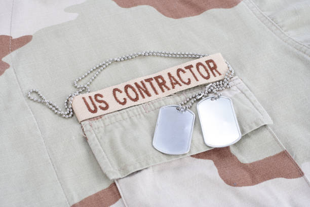istock US CONTRACTOR branch tape with dog tags patch on desert camouflage uniform 1021833482