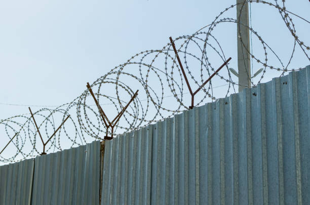 istock Metal fence with barbed wire on blue sky background 1021844488