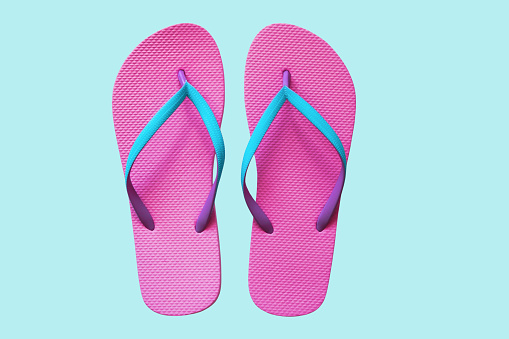 Pink flip flops isolated on blue background. Top view