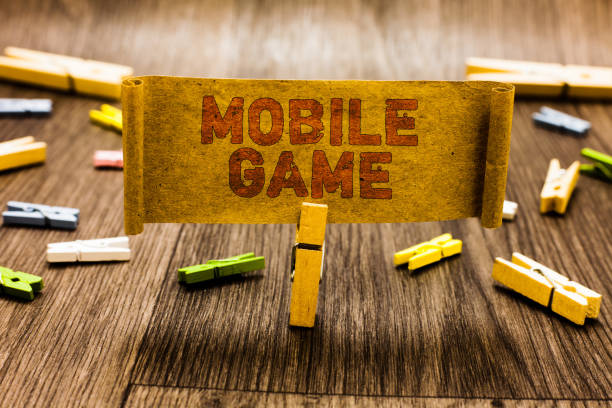 istock Word writing text Mobile Game. Business concept for they are entertaining programs made to work on smart device Clothespin holding old piece fabric several clothespins wooden floor. 1021889818