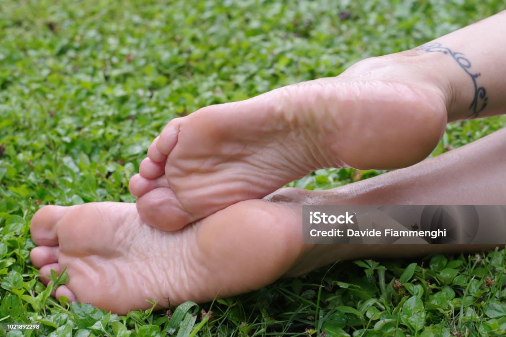 Suole dei piedi femminili bagnate sull'erba - Foto stock royalty-free di Adulto