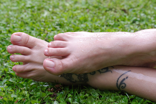 Wet female feet on grass with natural nails