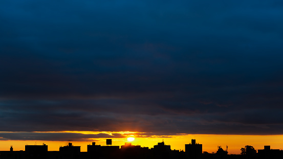 Front view of a beautiful sunset in the northern part of Porto Alegre for composition, showing the silhouette of buildings, and a sun with yellowish tones