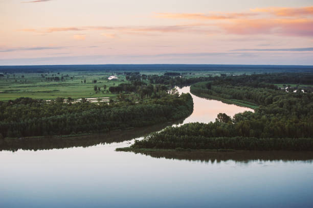 istock River flows along shore with forest with mist. Channel of river flows around island. Sunset glow in dawn reflected on water. Colorful morning mystical atmospheric landscape of majestic nature. 1021952644