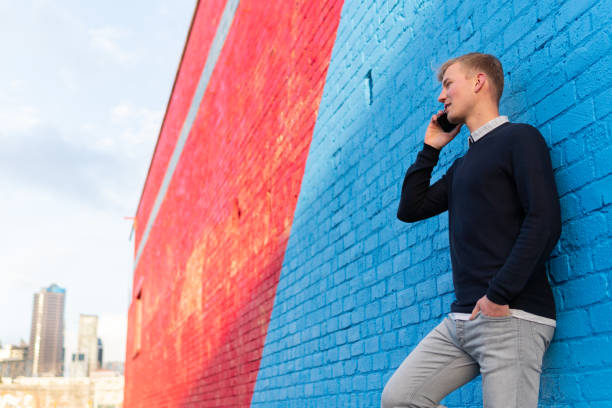 istock Young man leaning against a brick wall while using a smart phone 1021980970