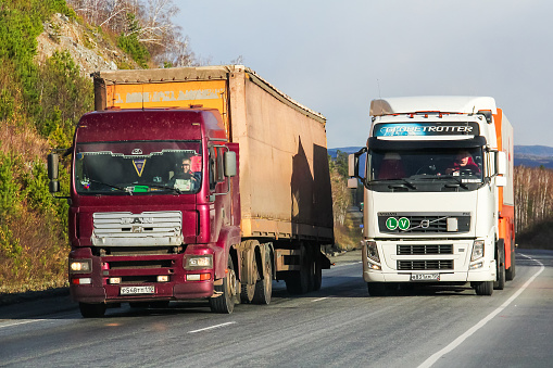 Chelyabinsk region, Russia - October 9, 2015: Semi-trailer trucks MAN TGA and Volvo FH12 at the interurban road.