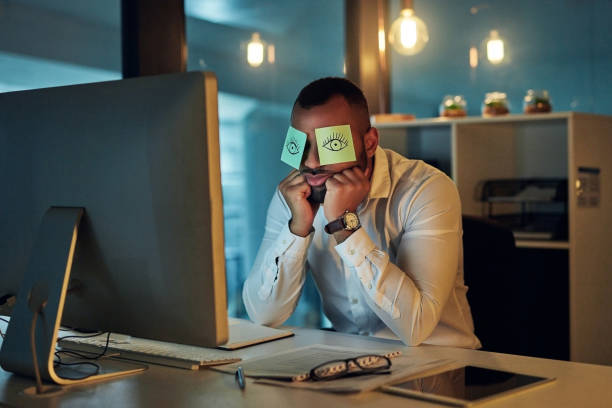 The silly side of work stress Shot of a tired young businessman working late in an office with sticky notes covering his eyes laziness photos stock pictures, royalty-free photos & images