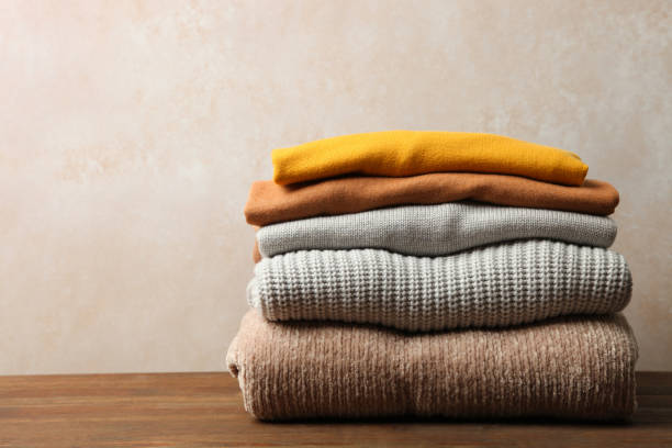 autumn clothes Pile of female warm sweaters on wooden table on neutral background. Concept autumn clothes. top garment stock pictures, royalty-free photos & images