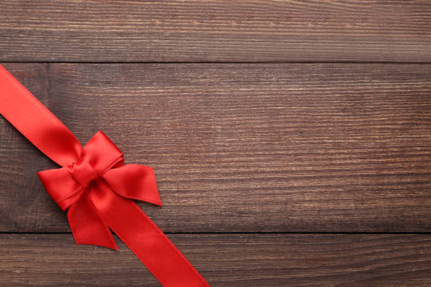 istock Red bow with ribbon on brown wooden table 1022066526