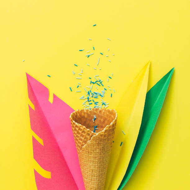 Waffle cone of ice cream lies among palm tropical leaves made of paper on yellow background Waffle cone of ice cream lies among palm tropical leaves made of paper on yellow background. Summer vacation party concept neon sign ice cream stock pictures, royalty-free photos & images