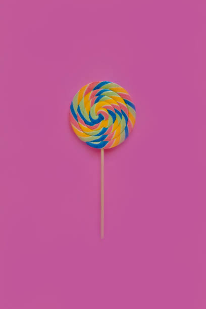 istock A multicolored round lollipop on a bright pink background. 1022081624