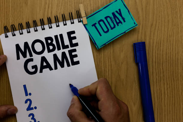 istock Word writing text Mobile Game. Business concept for they are entertaining programs made to work on smart device Man holding marker notebook clothespin reminder wooden table cup coffee. 1022081776