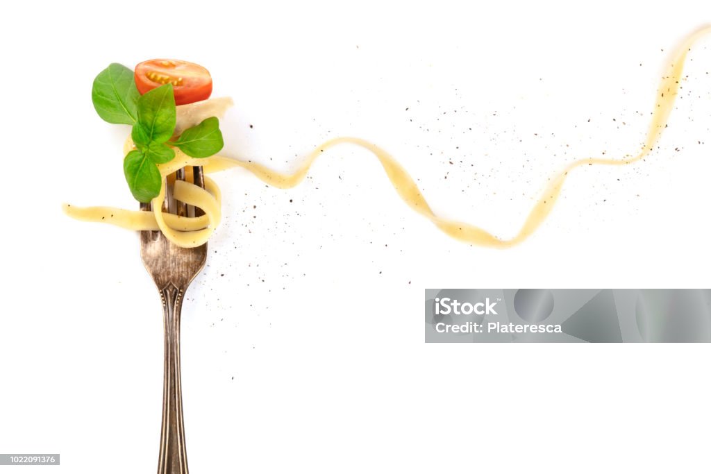 Italian pasta. Overhead photo of vintage fork with pappardelle, basil, cheese, and tomato, on white background Italian pasta. An overhead photo of a vintage fork with pappardelle, basil, cheese, tomato, and pepper, on a white background with copyspace Food Stock Photo