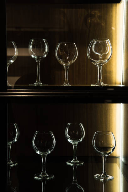 different wineglasses on shelves in kitchen with dark light