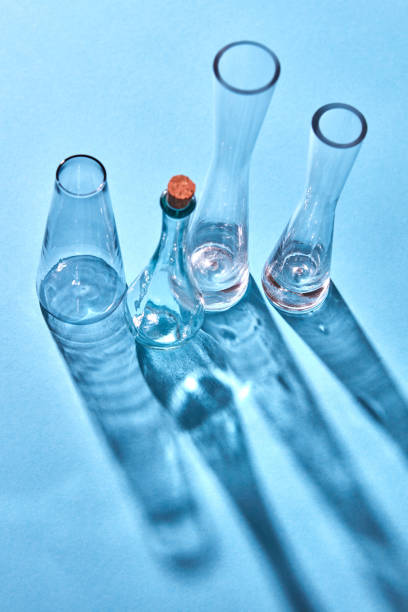 istock A glass empty bottles on a blue paper background with long shadows and reflection. 1022098130