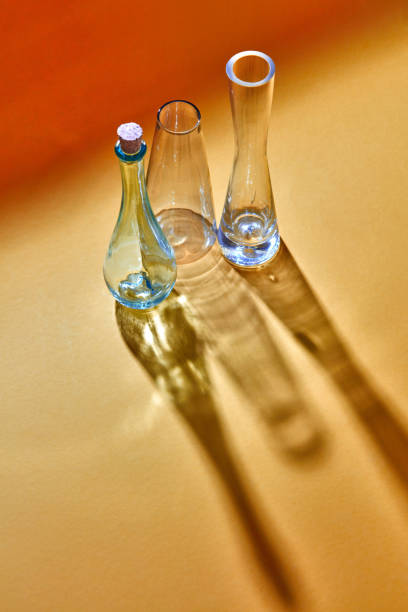 istock Three glass bottles empty on a duotone yellow paper background with diagonal shadows and reflection. 1022100708