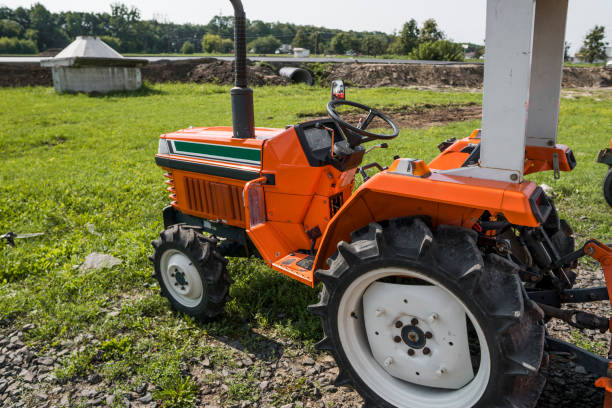 istock A small mini orange tractor stands on a farm yard on green grass and waits for work to begin. 1022113086