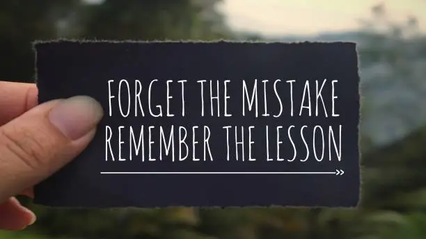 ‘Forget the mistake, remember the lesson’ written on a black paper. Vintage styled background.