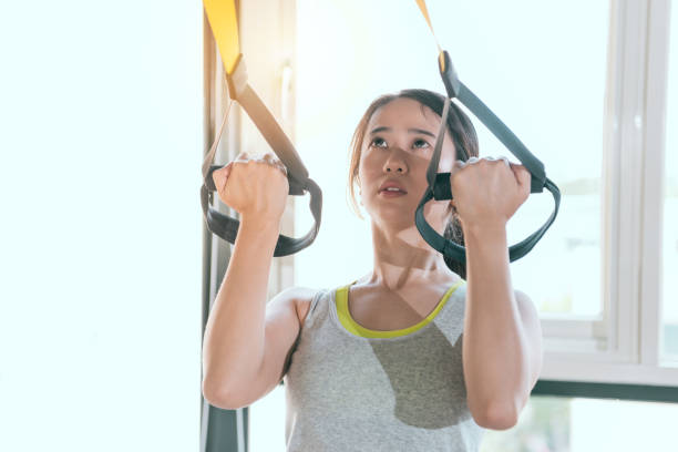 istock charming Asian girl pulls up hard with TRX 1022113518
